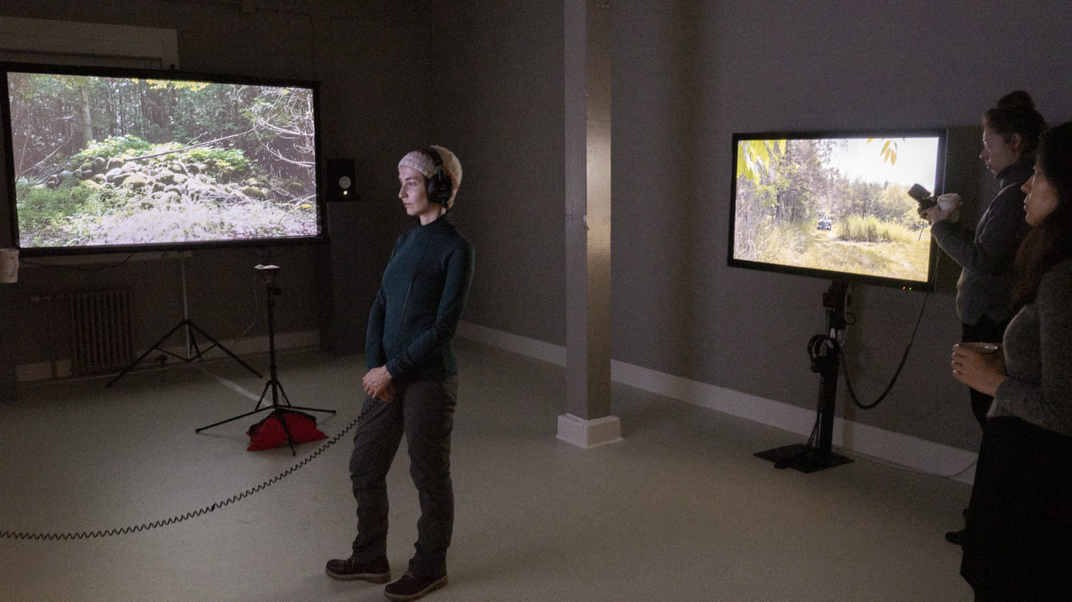 Image of student looking at video installation with three large video screen 